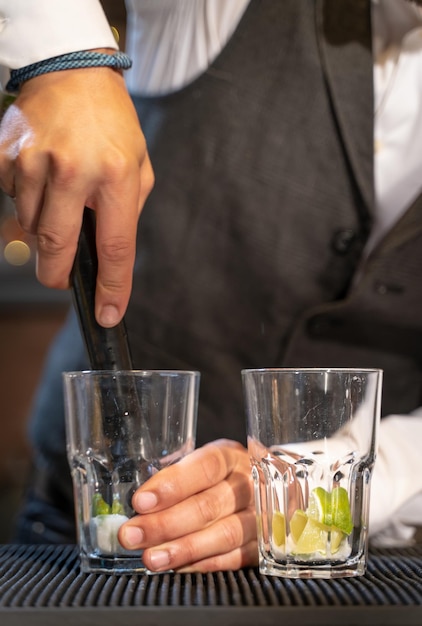 Elegant barman making cocktail Mojito in night club adding ingredients and creating expert drinks on bar counter