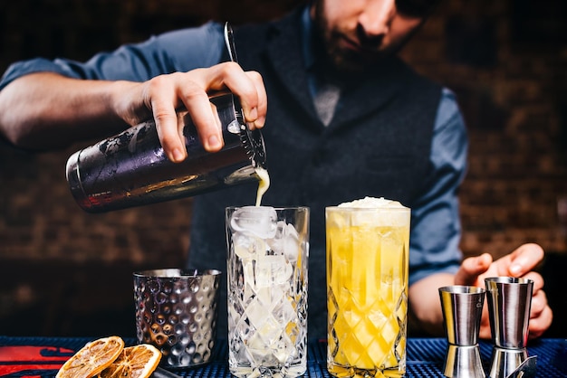 优雅的酒保照片注入新鲜橙伏特加鸡尾酒在冰水晶玻璃器皿