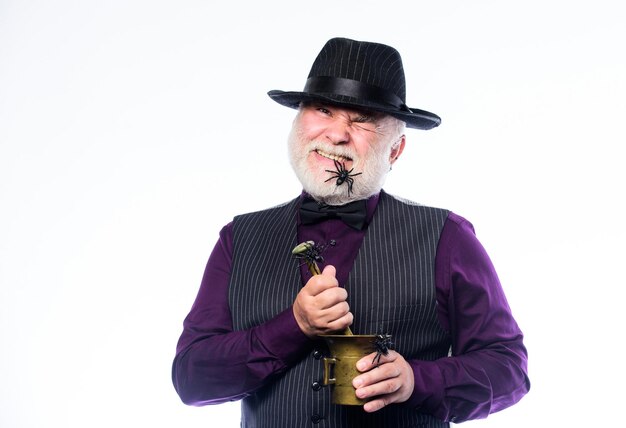 Elegant bartender wear hat and vest prepare drink Horror party Frightening bartender Weird old bartender with gray beard and spider Preparing magic drink Halloween concept Strange people