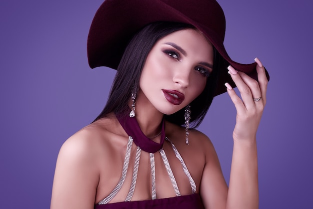 Elegant beautiful brunette woman in a violet dress and wide hat