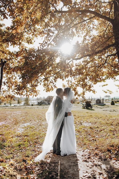 Elegant beautiful couple under veil standing in front and looking at each other