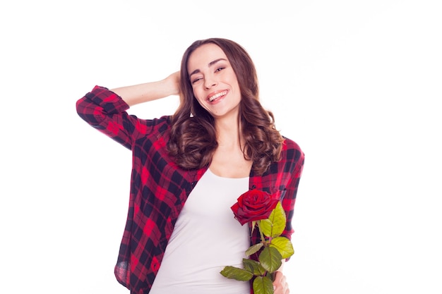 Elegant beautiful happy woman in casual clothes with one blossom of red rose is posing 