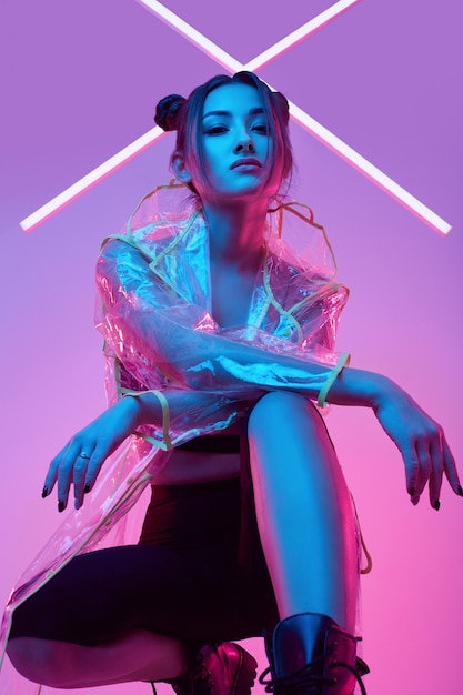 Foto elegante bella donna in un impermeabile intorno al neon luminoso colorato