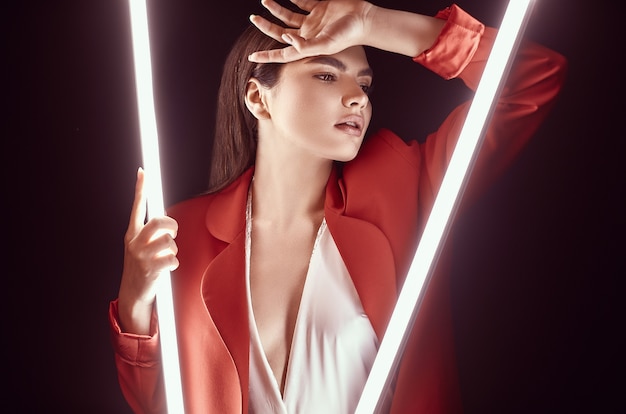 Elegant beautiful woman in a red fashionable suit posing with neon lights