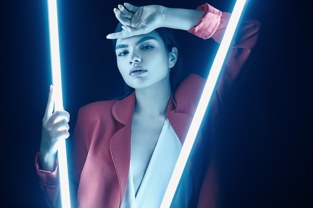 Elegant beautiful woman in a red fashionable suit posing with neon lights