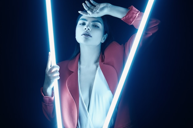 Elegant beautiful woman in a red fashionable suit posing with neon lights