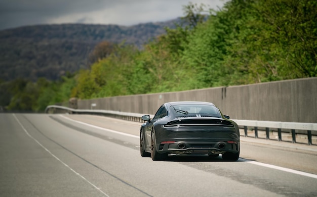 Elegant black modern twodoor German roadster Brand new black luxury carrera sports car on the highway