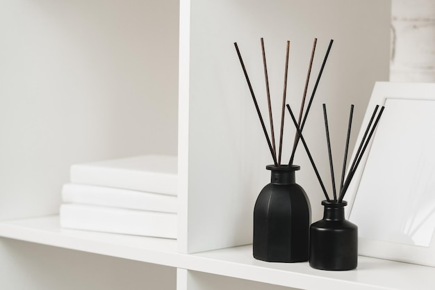 Elegant black reed diffuser on white shelf in minimalist home decor setting