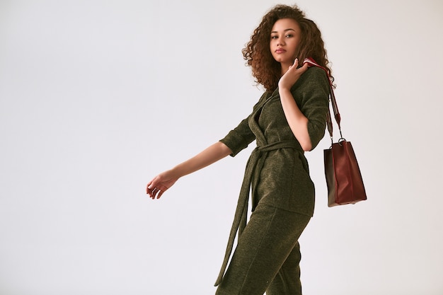 Elegant black woman with curly hair in fashionable green suit