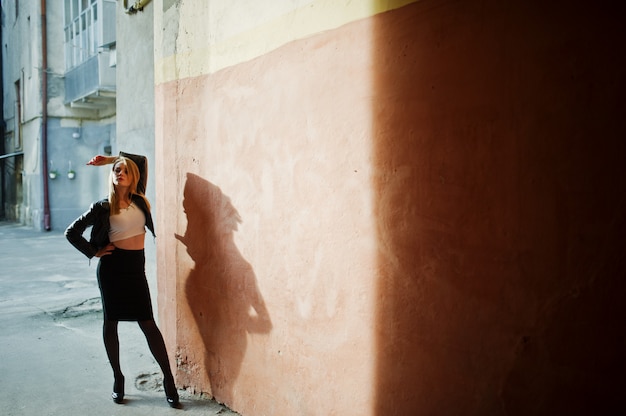写真 エレガントなブロンドの女の子は、影、古い壁の町の通りでポーズ黒革のジャケットに着用します。