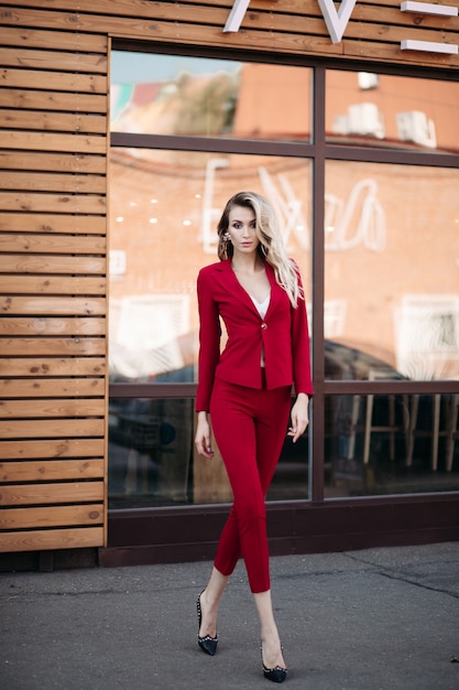 Foto elegante donna bionda in abito rosso scuro con bottoni d'oro