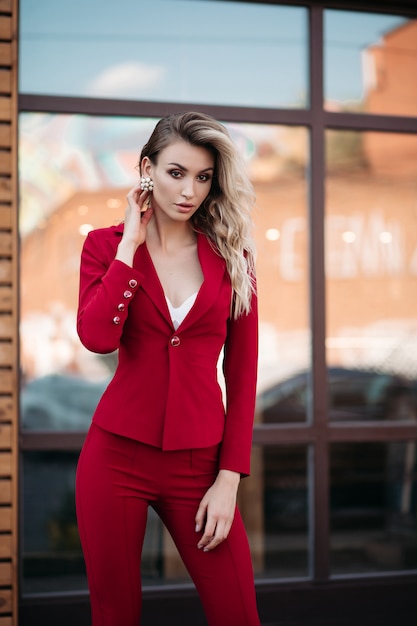 Elegant blonde woman in dark red suit with gold buttons