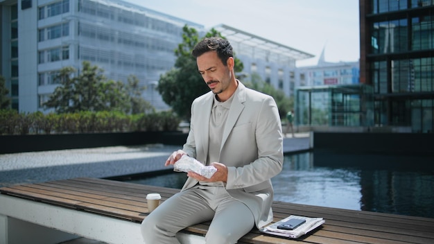 Photo elegant boss unpacking lunch sunny park business man enjoying sandwich at bench