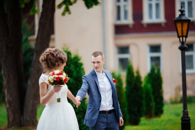 エレガントな花嫁と花婿の結婚式の日に屋外で一緒にポーズ