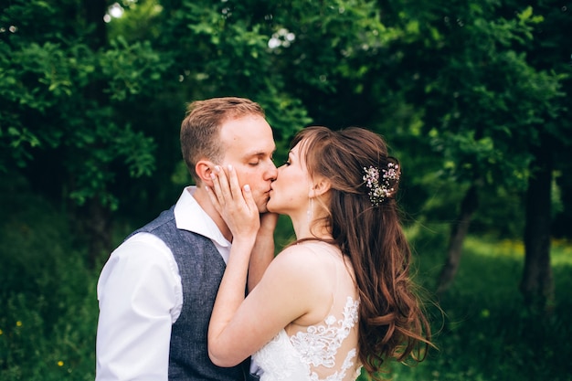 Elegante sposa e sposo che propongono insieme all'aperto in un giorno di nozze