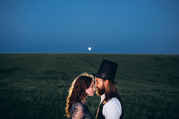 Sposa e sposo eleganti che camminano e che posano sul campo verde