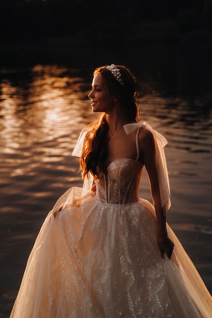 An elegant bride in a white dress enjoys nature at sunset.Model in a wedding dress in nature in the Park.Belarus