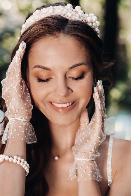 Элегантная невеста в белом платье, перчатках с букетом на водопаде в парке