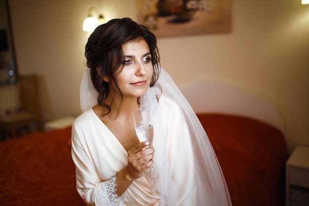 Elegant bride in white robe posing under curtain Amazing bride in the morning preparation