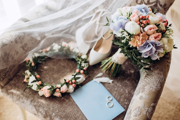 Elegant bruidsboeket met lint, trouwkaarten, verlovingsringen en schoenen voor de bruid