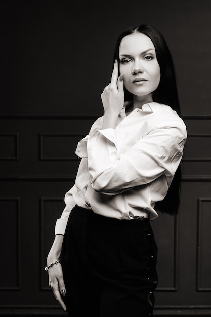 Elegant brunette in a white shirt on a dark background.black and white photo