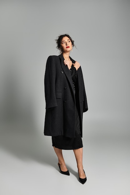 elegant brunette woman in stylish black attire poses gracefully in studio setting