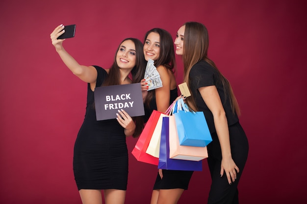 Elegant brunette women wears black dress holding shopping bags, black friday 