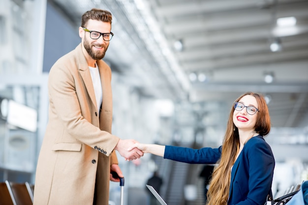 Elegant businessman in the coat meeting businesswoman at the waiting hall of the airport