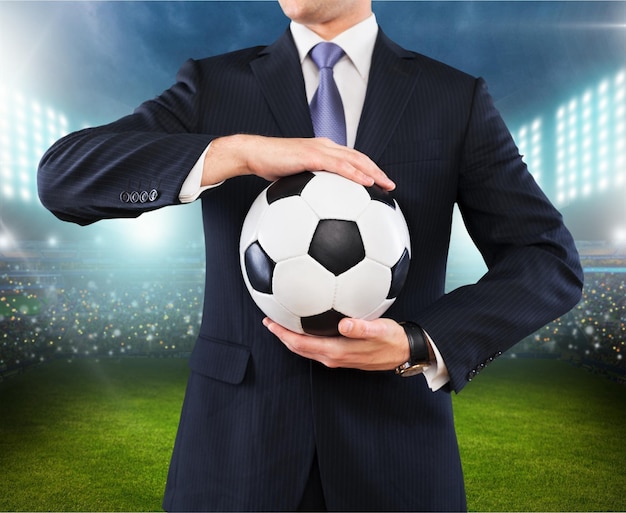 Elegant businessman holding a soccer ball, close up