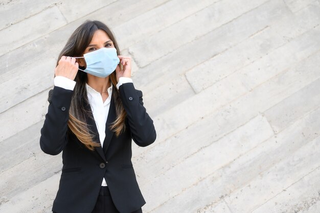 Photo elegant businesswoman put on protective face mask outdoors