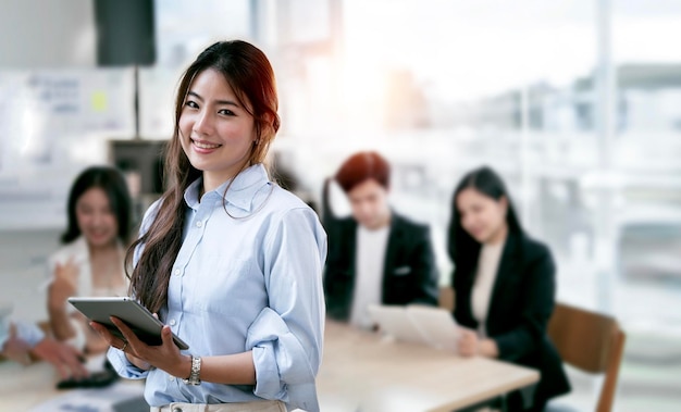 Donna di affari elegante che sta nell'ufficio con la compressa digitale