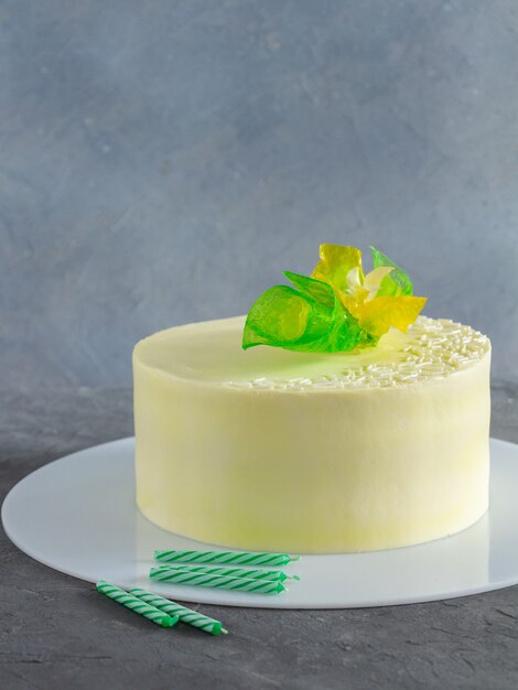 Elegant cake with yellow, green flowers decoration and birthday candles on grey