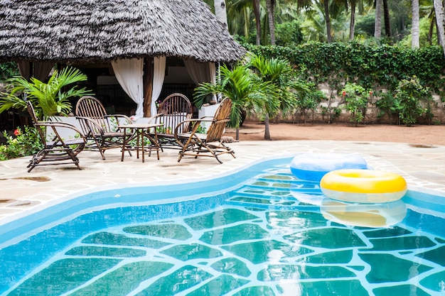 Elegant chairs made of wood close to a swimming pool inside a Kenyan garden