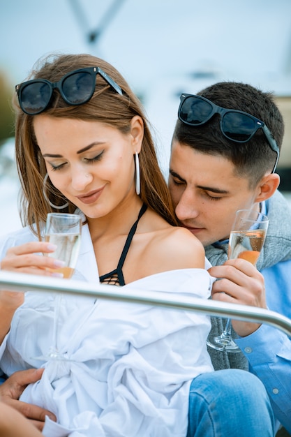 Elegante coppia innamorata. ricco uomo pulito che bacia nella spalla della donna di lusso con champange di vetro. incontri romantici sulla barca. concetto di vacanza.