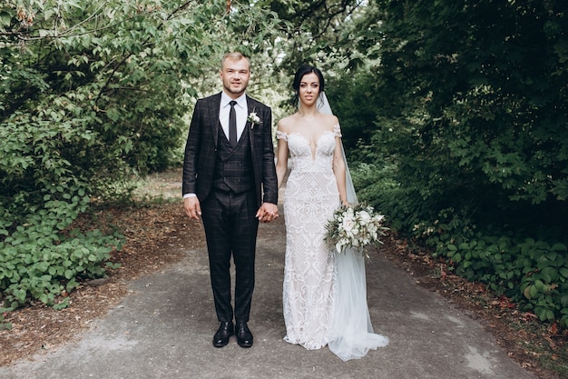 Foto coppie eleganti che camminano al tramonto, storia d'amore, ritratto della sposa e dello sposo il giorno del matrimonio