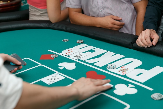 Elegant croupier in poker puts cards on a table with chips.