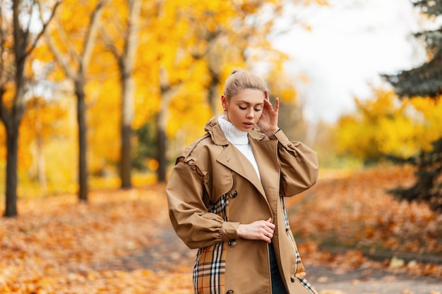 Elegant cute young woman in a stylish coat with a trendy hairstyle posing