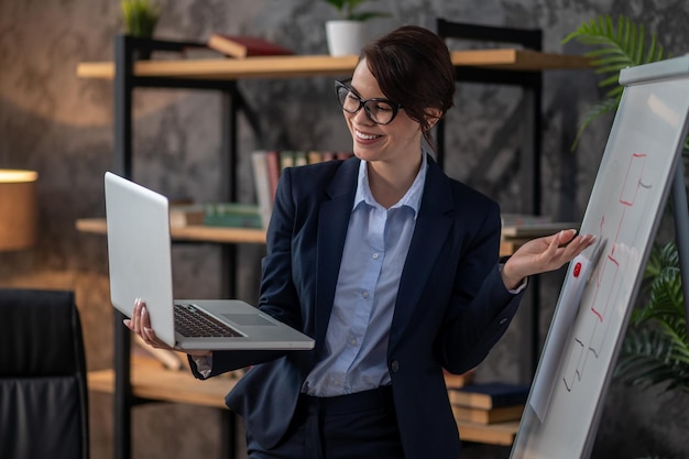 Elegant darkhaired woman presenting something to online audience