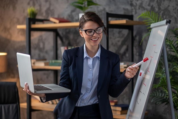 Elegant darkhaired woman presenting something to online audience