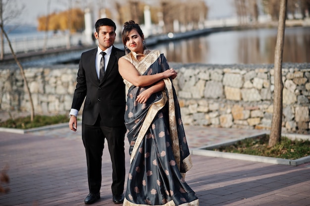 Elegant and fashionable indian friends couple of woman in saree and man in suit dancing together outdoor.