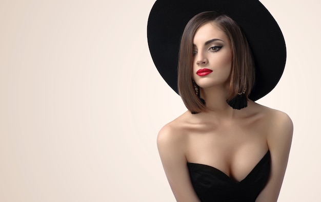 Elegant fashionable lady posing wearing a hat in studio