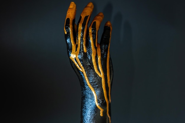 검은 배경을 가진 그녀의 피부에 검은색과 금색 페인트를 칠한 우아한 여성 손