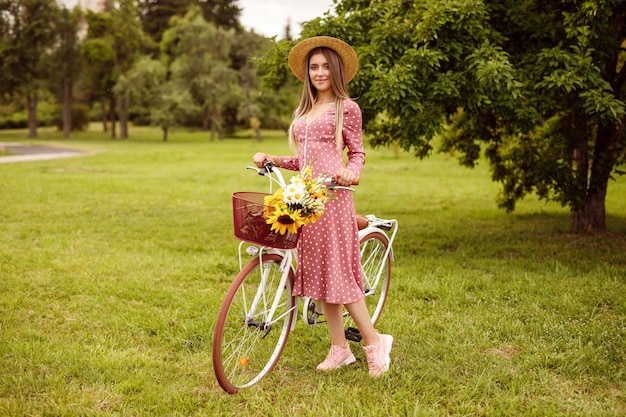 Elegant female with vintage bike standing on park lawn