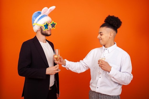 Elegant gay African American boy offering a glass of champagne to funny caucasian man