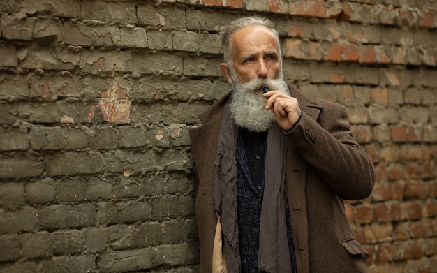 Foto elegante signore con barba lunga fumare all'aperto.