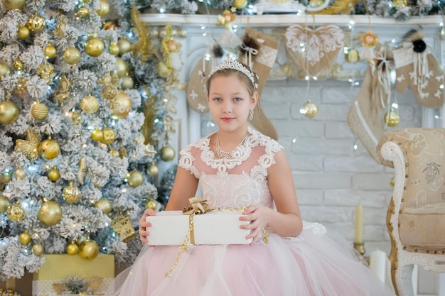 Elegant girl at the New Year tree with a gift