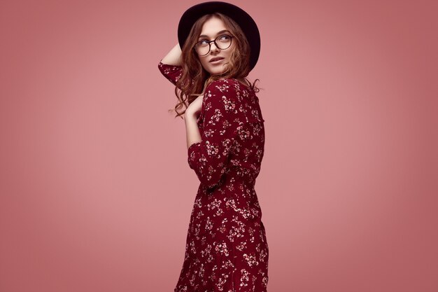 Elegant glamor hipster girl in red fashion dress, black hat and glasses