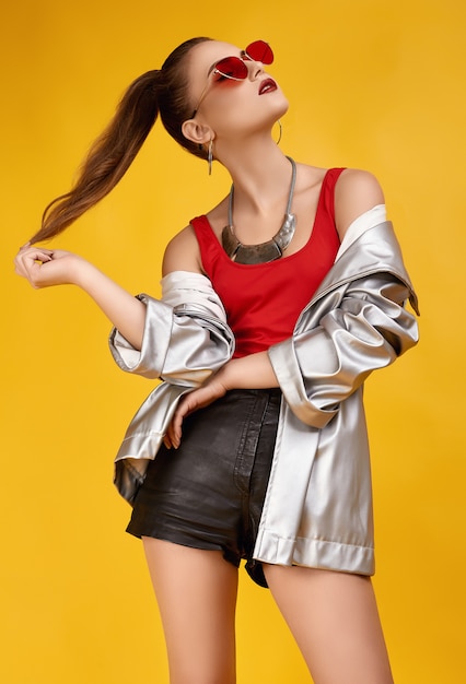 Elegant glamor hipster girl in red top, black shorts and jeans jacket