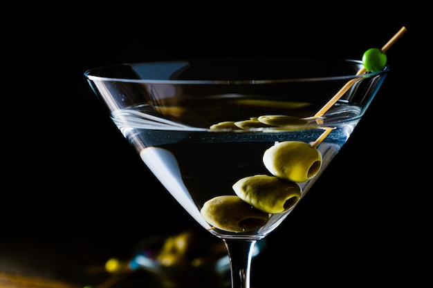 An Elegant glass of dry martini with olives on a black background. Horizontal orientation.