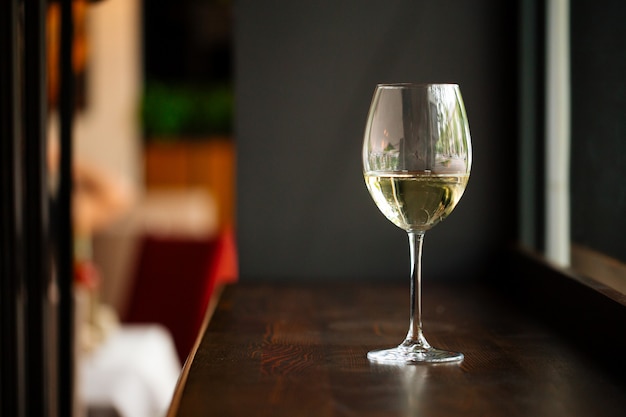 Elegante bicchiere di vino bianco sul bancone bar in legno